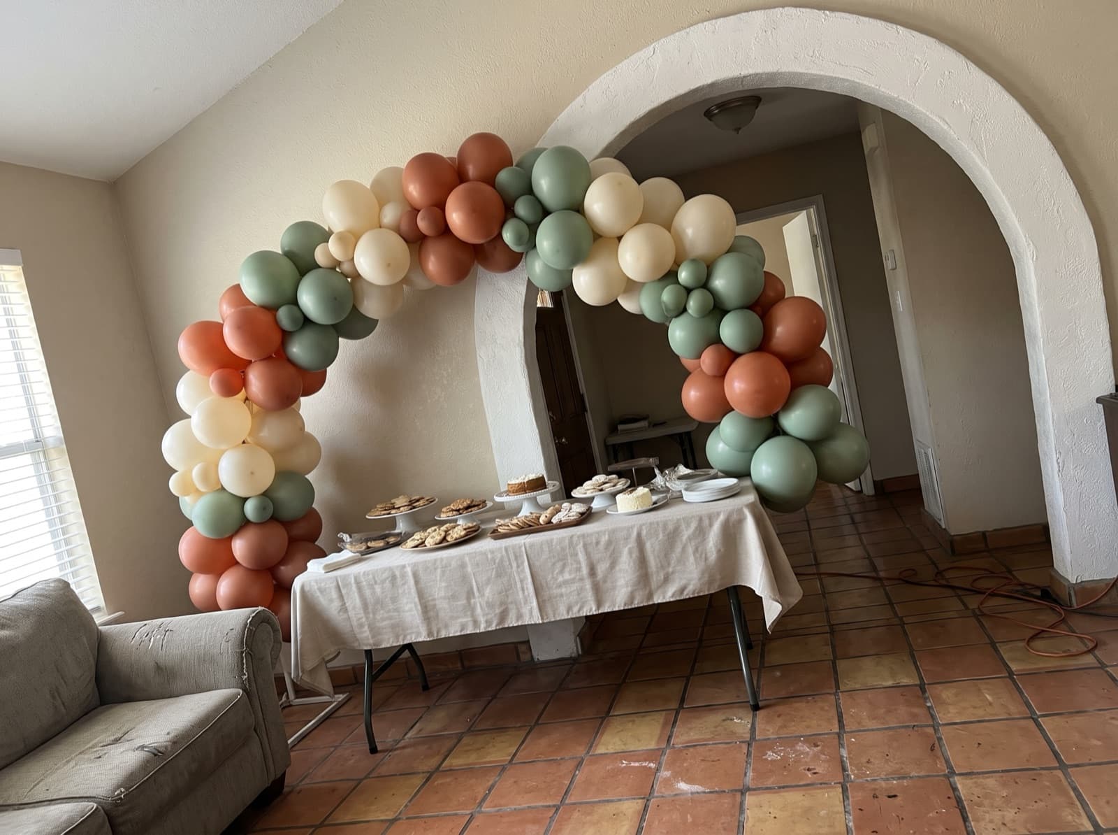 Organic balloon arch in terracotta, cream and sage over a dessert table in a San Antonio home