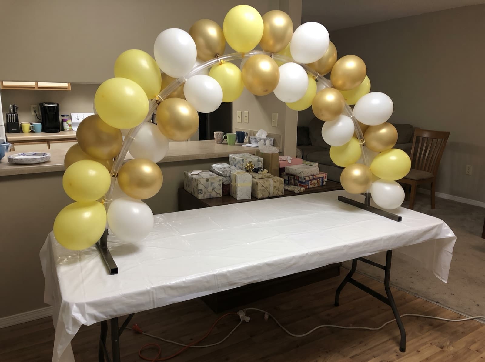 Mini tabletop balloon arch in butter yellow and white over a gift table