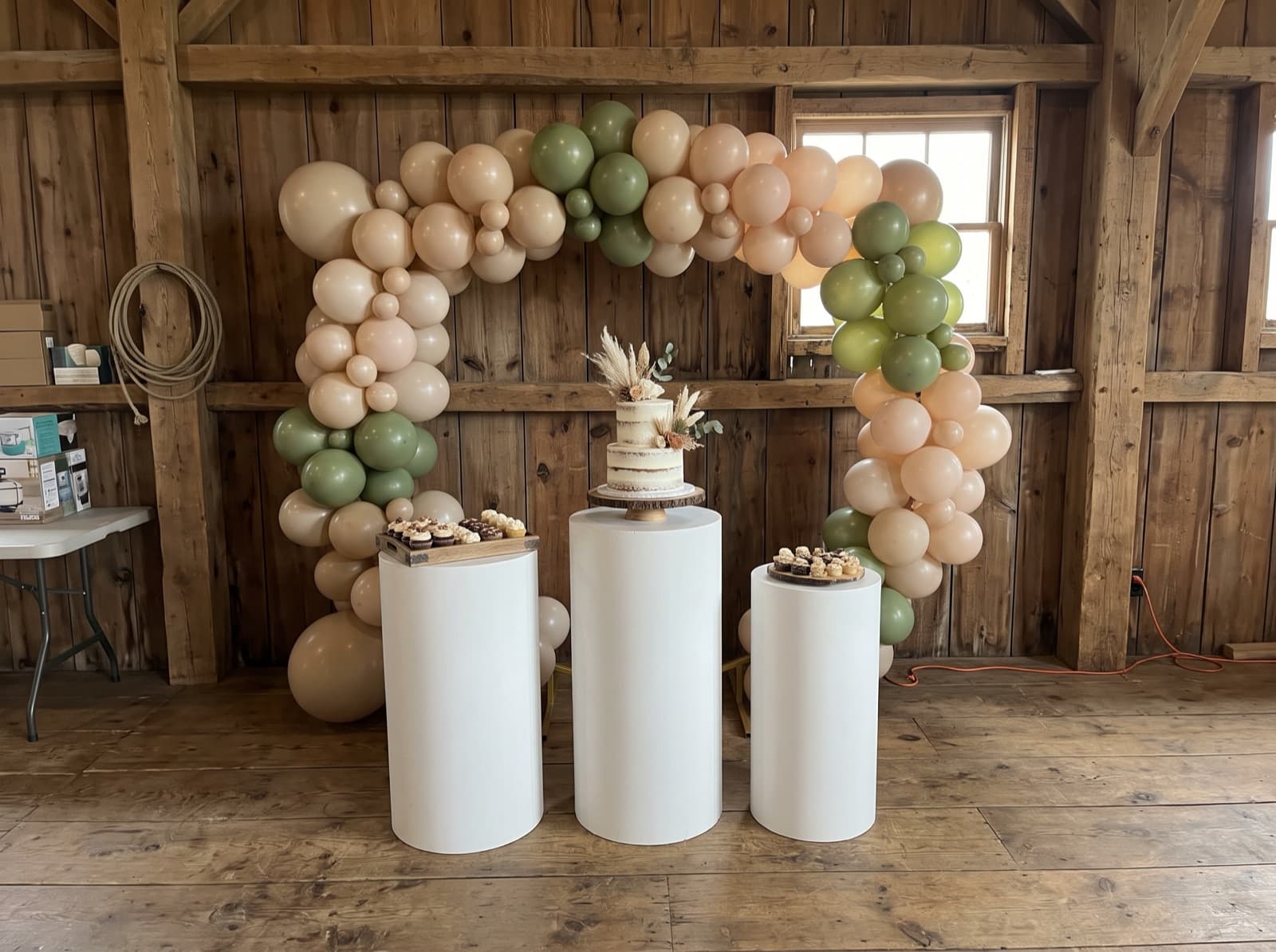Backdrop with pedestals and a cake table in a barn venue