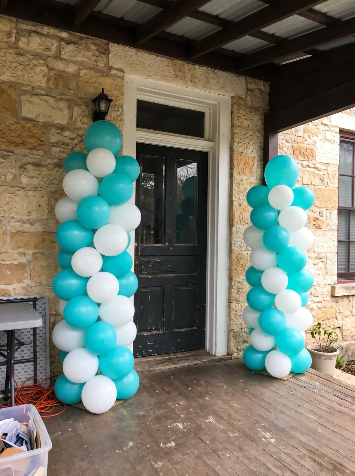 Pair of turquoise and white spiral balloon columns at a front door