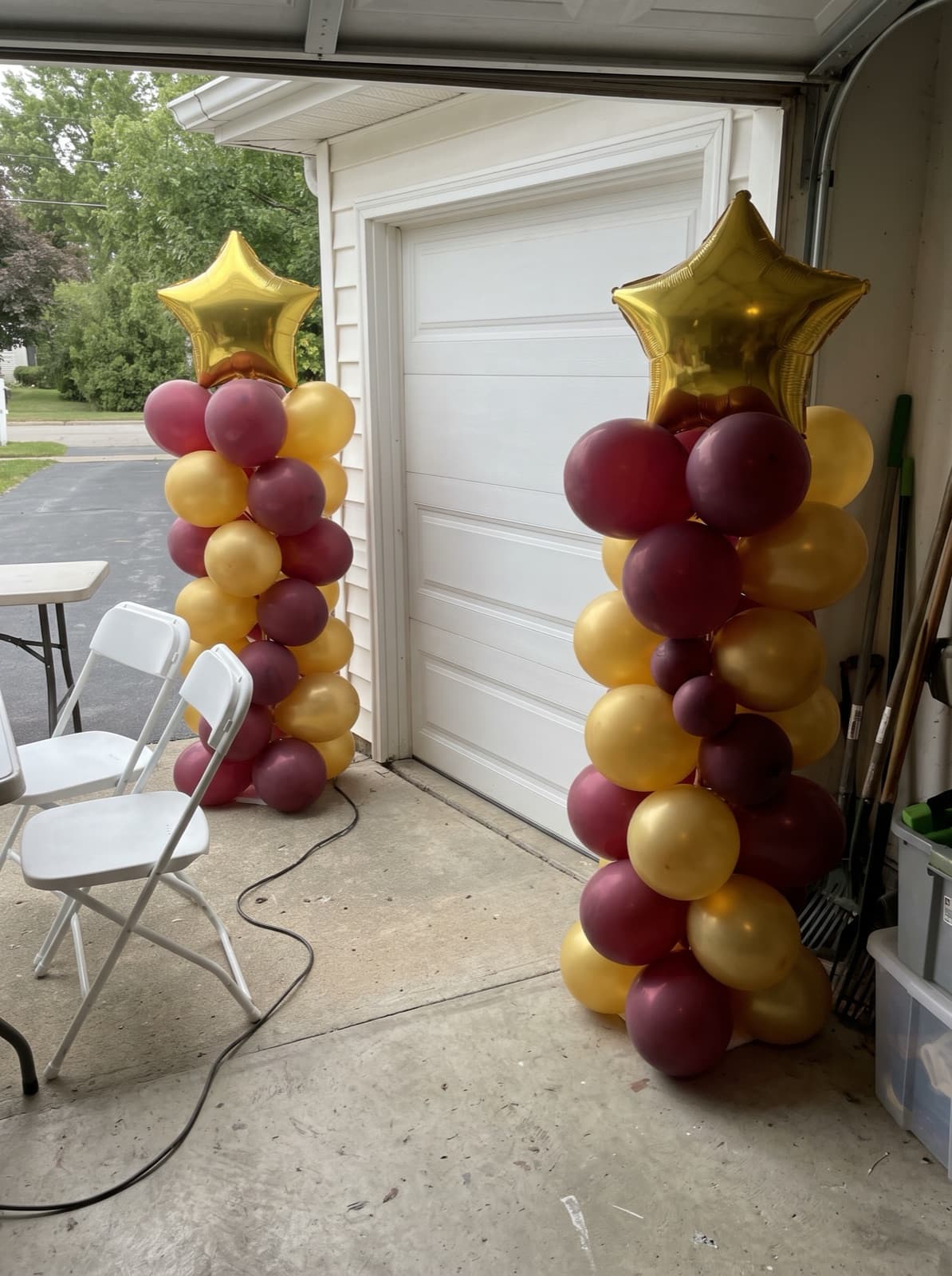 Maroon and gold balloon columns with star toppers for a graduation
