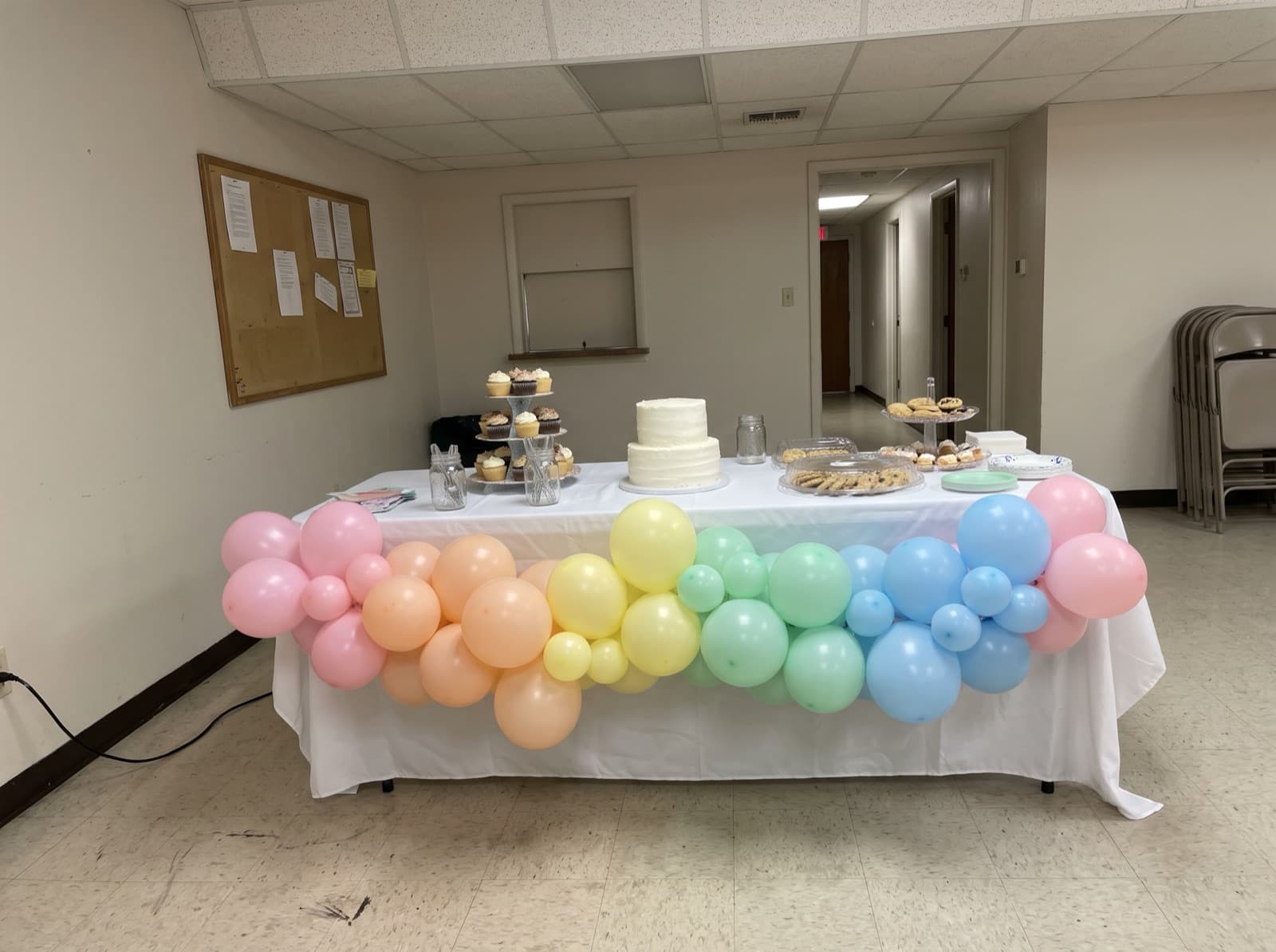 Pastel balloon garland across the front of a cake table