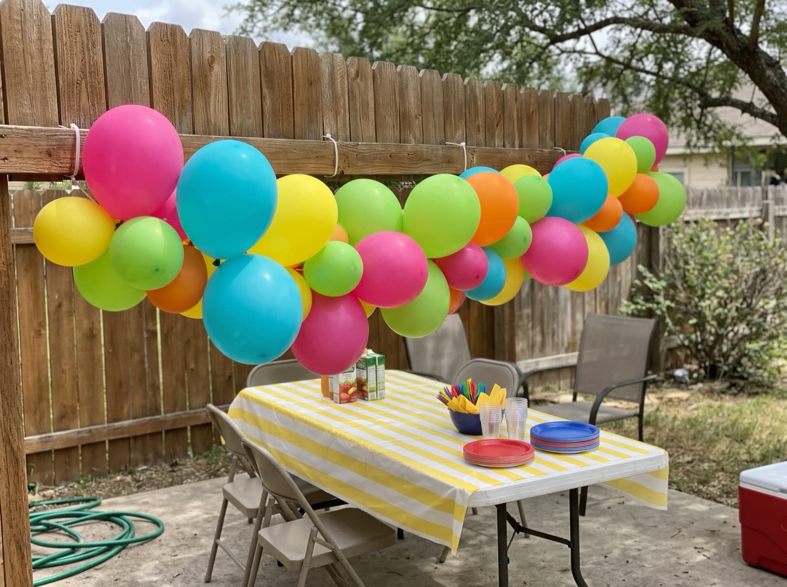 Bright balloon garland on a backyard cedar fence