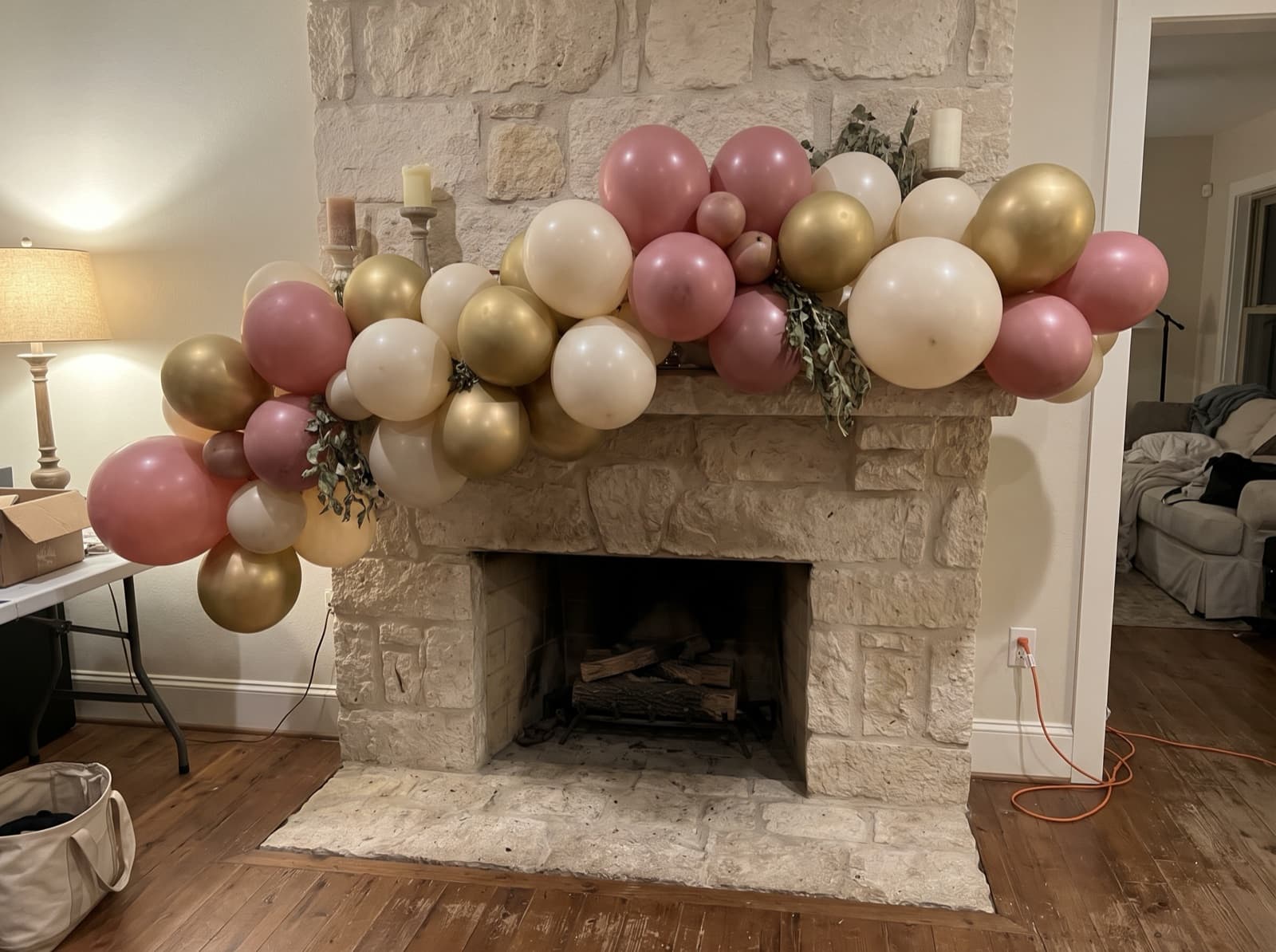 Organic balloon garland in dusty rose, ivory and gold along a limestone fireplace mantel in a San Antonio home