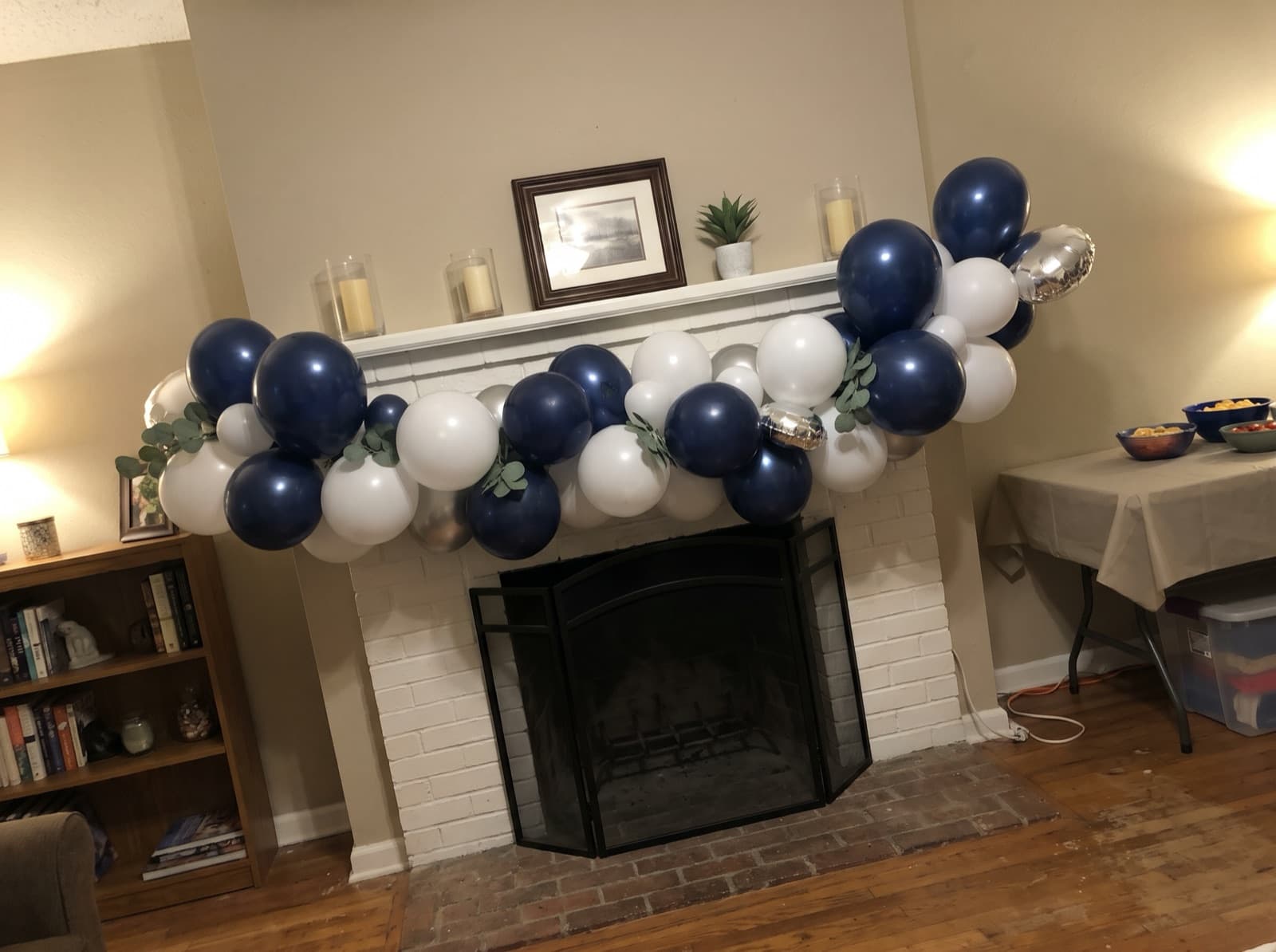 Navy, white and silver balloon garland along a painted brick mantel
