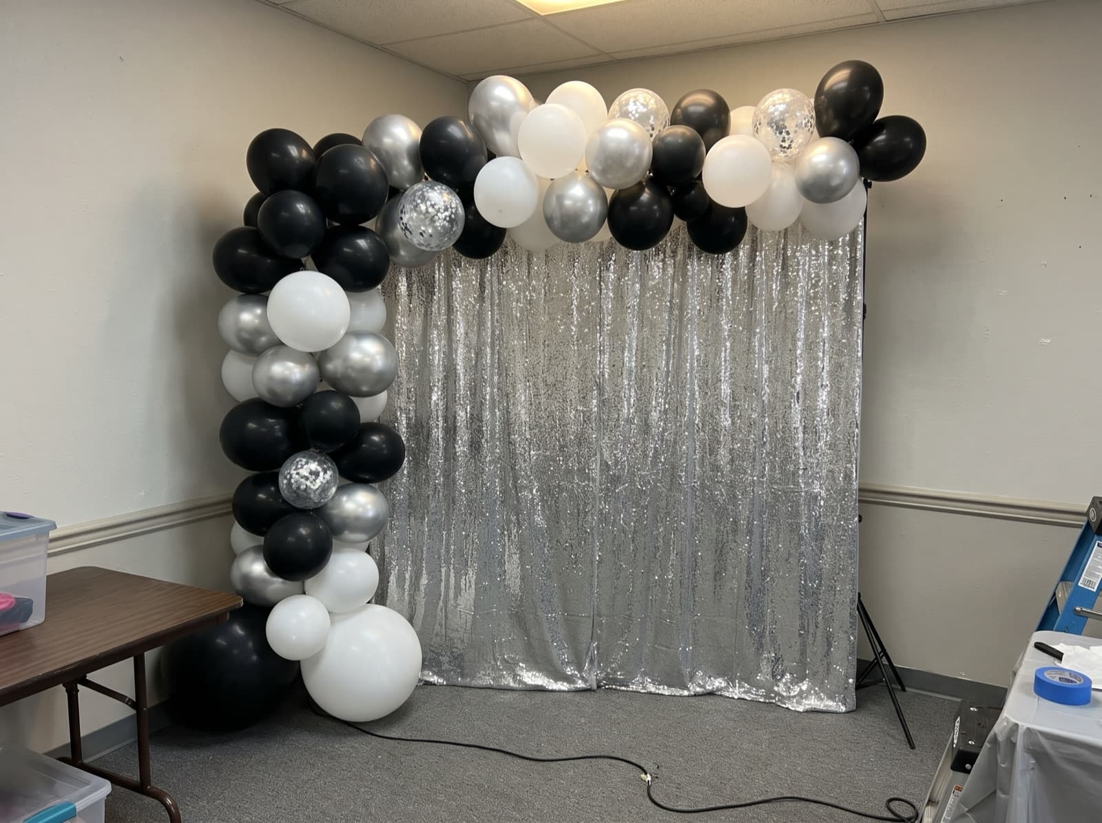 Black, white and silver balloon garland over a silver shimmer wall