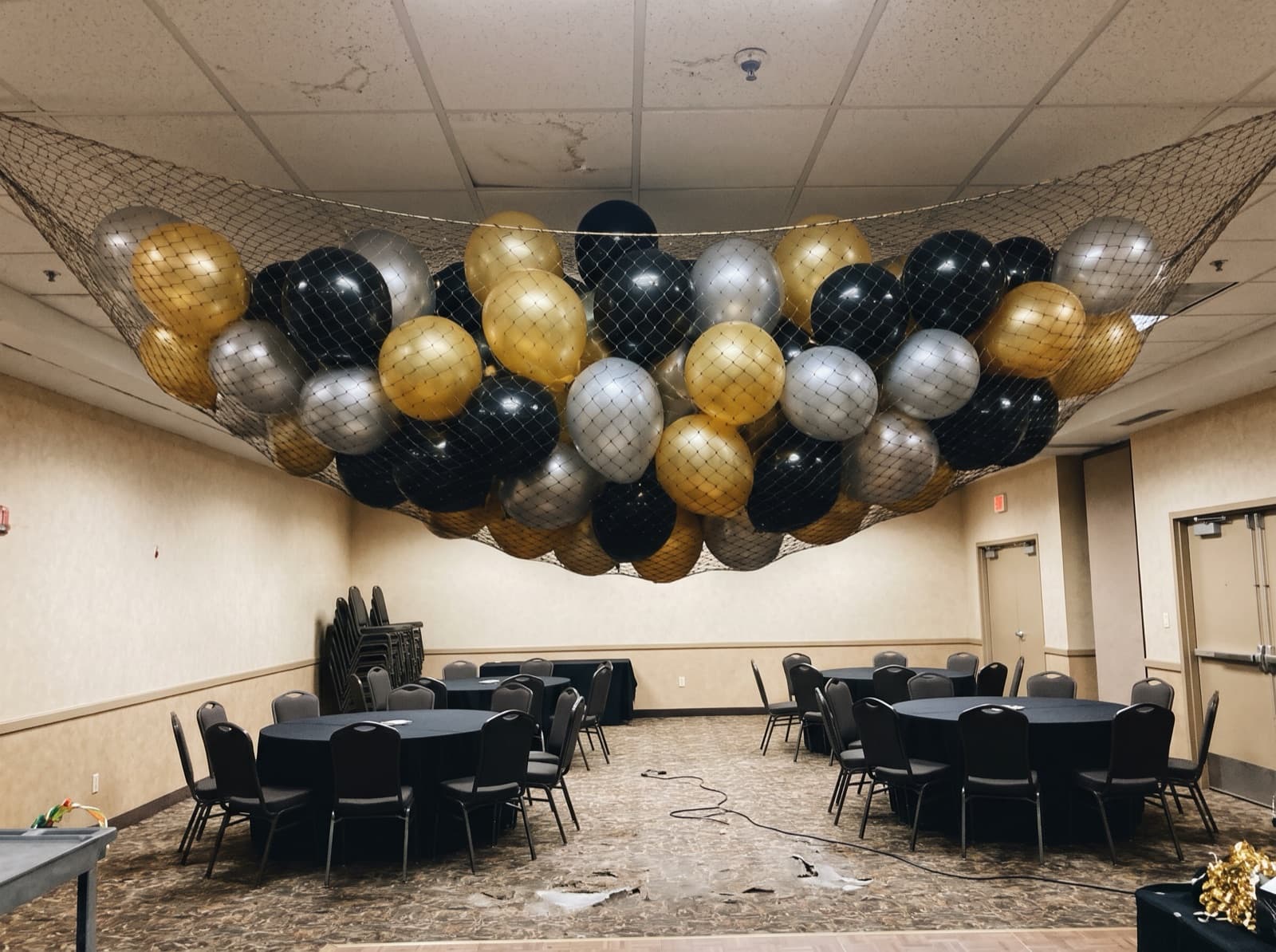 Balloon drop net full of balloons near a ballroom ceiling