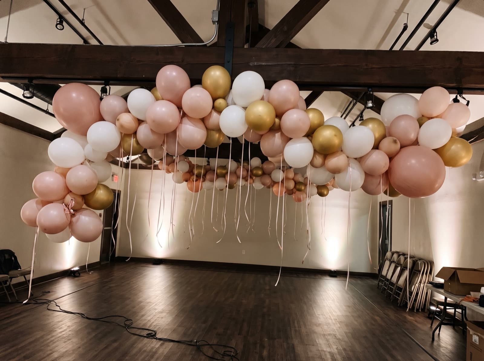 Balloon ceiling of blush, white and gold balloons over a dance floor at a San Antonio event hall