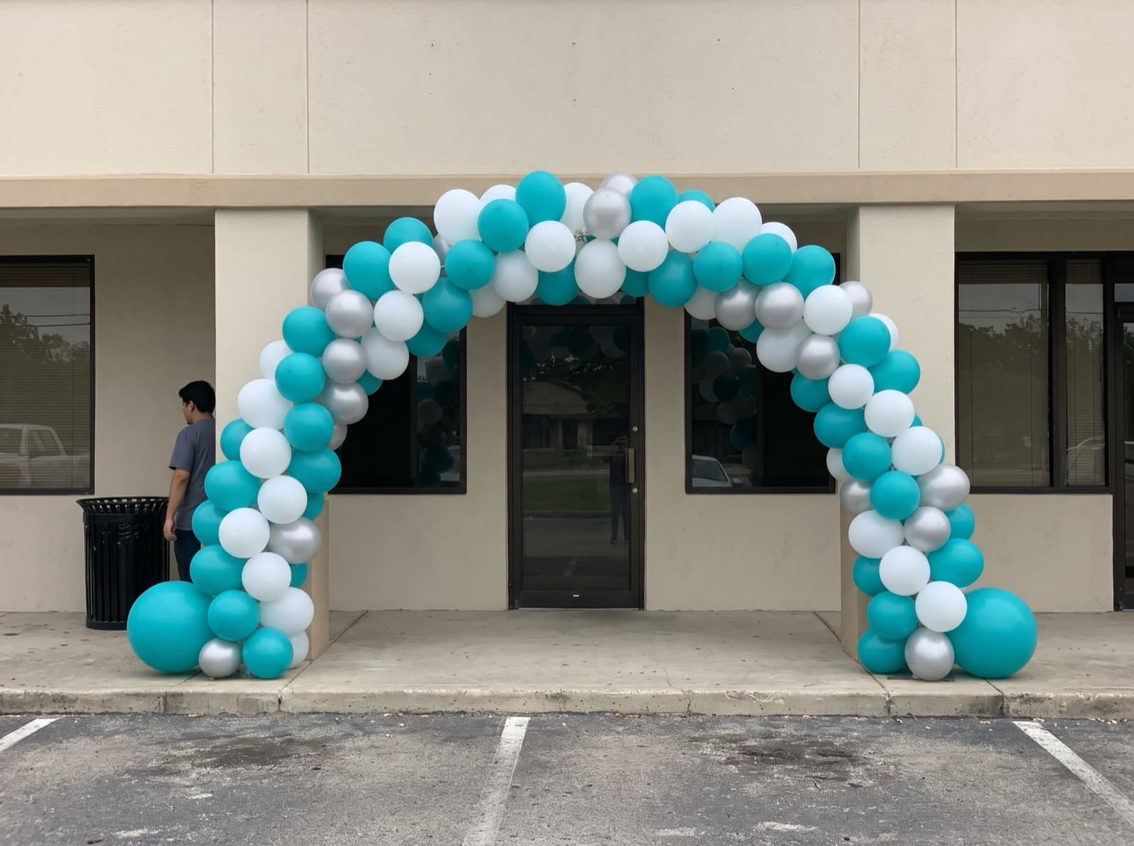 Giant teal, white and silver balloon arch over a storefront