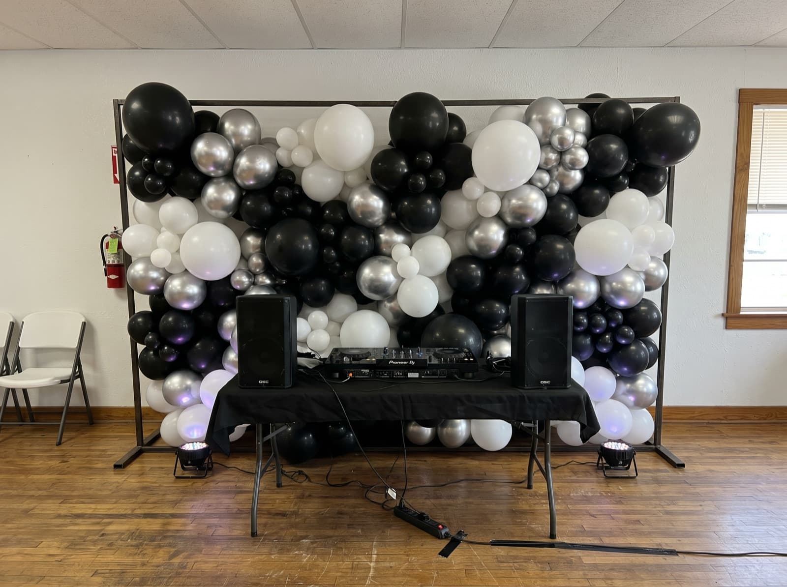 Silver, black and white balloon wall behind a DJ booth
