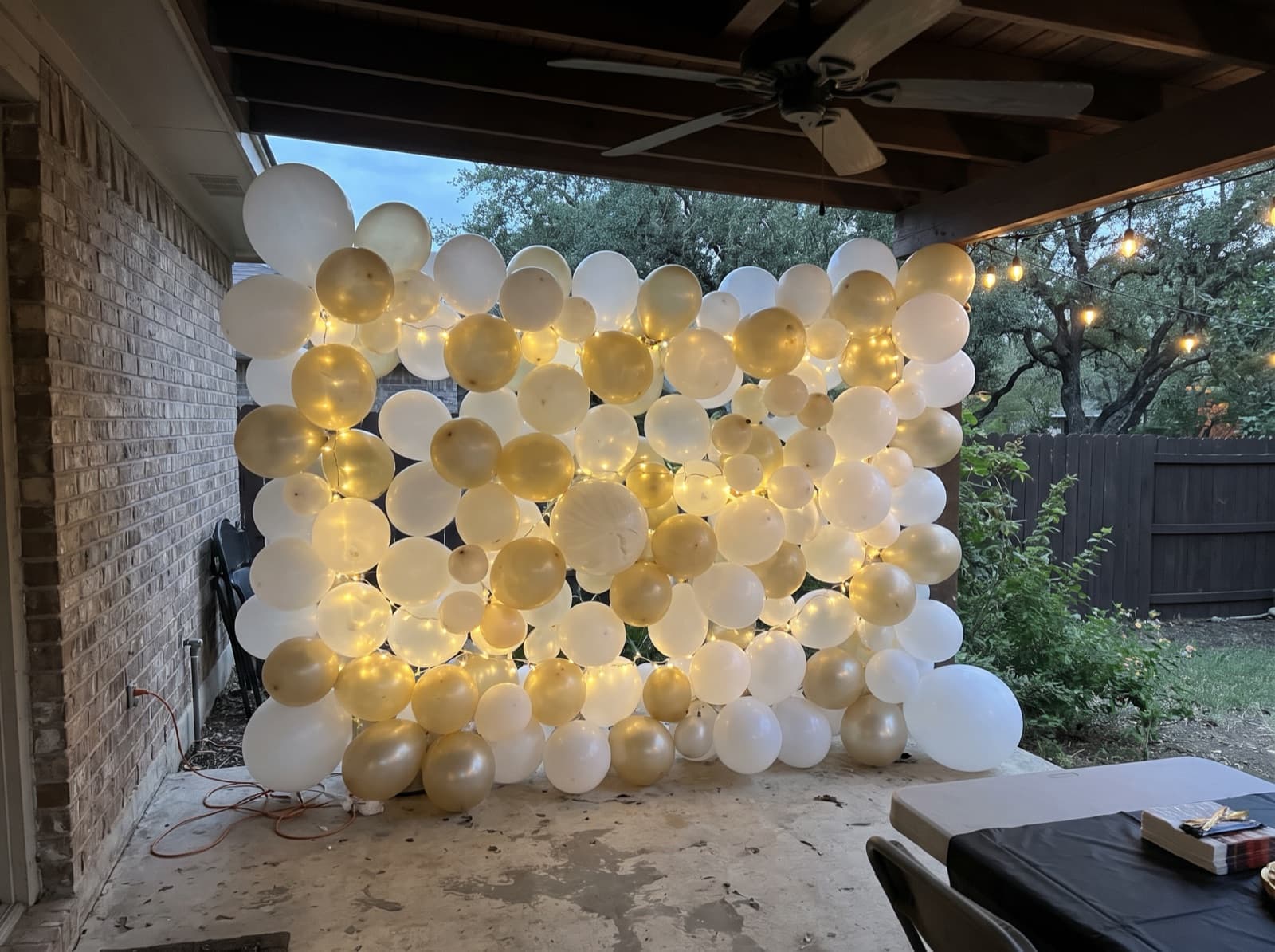 Balloon wall with string lights on a covered patio